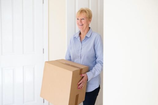 Senior woman carrying a box of items to donate.